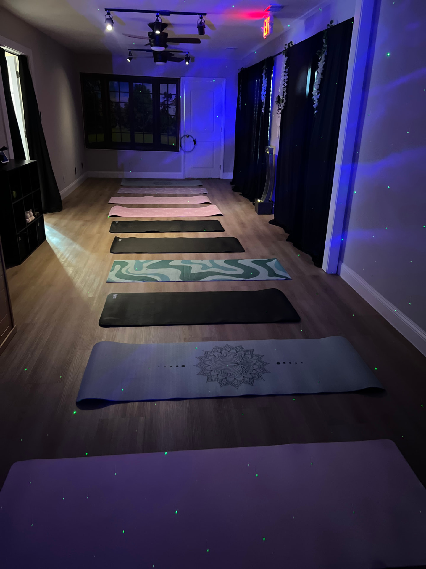 Mats laid out in rows across the warm wood floor of the Marietta breathwork studio under soft blue light
